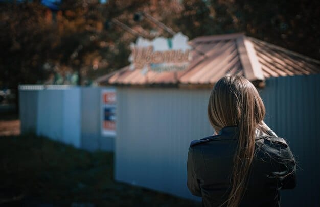 A homeowner looking concerned while reviewing a complex home insurance policy, with a backdrop of a blurred house and a subtle wildfire glow in the distance, representing the increasing challenges.