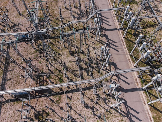An aerial view of a sprawling, busy US power substation with multiple transformers and high-voltage lines, shimmering slightly from heat, illustrating the complexity and potential stress on grid infrastructure during peak demand.