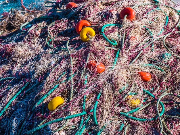 A detailed close-up shot of various types of plastic debris, including bottle caps, fishing line, and foam fragments, meticulously sorted and laid out on a white tarp for scientific analysis during a coastal clean-up.