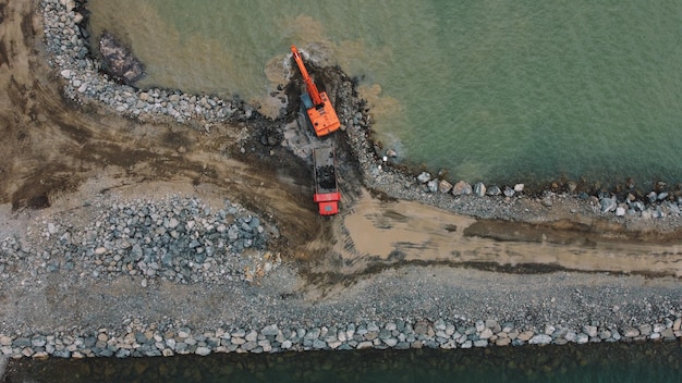 A drone view of a construction site for a new coastal barrier, showing heavy machinery alongside efforts to protect delicate marshland, symbolizing the balance between development and environmental preservation.