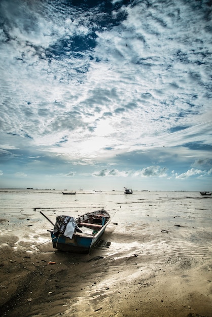 A fishing boat struggling in rough, choppy waters, with ominous clouds overhead, symbolizing the challenges faced by the fishing industry due to climate change.