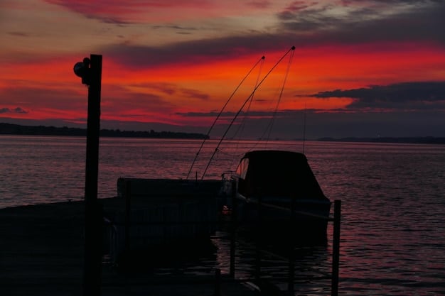 A fishing boat in calm waters, with a specialized ropeless fishing gear system being deployed. The sun is setting, casting a warm glow over the scene.