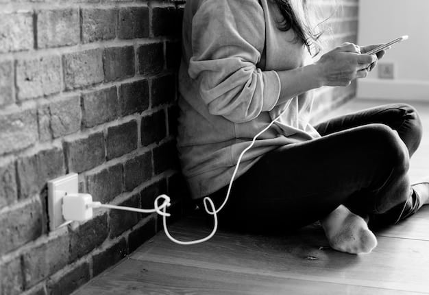 A person unplugging a phone charger from a wall outlet after their phone is fully charged, symbolizing conscious electronic usage and reducing phantom load.