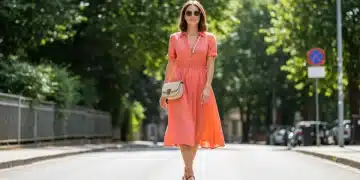 Woman in vibrant summer dress, sandals, cross-body bag, and sunglasses, embodying affordable 2025 summer style.