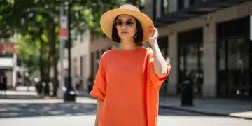 Woman in light linen dress, straw hat, and sunglasses, representing 2026 summer style for heatwave.